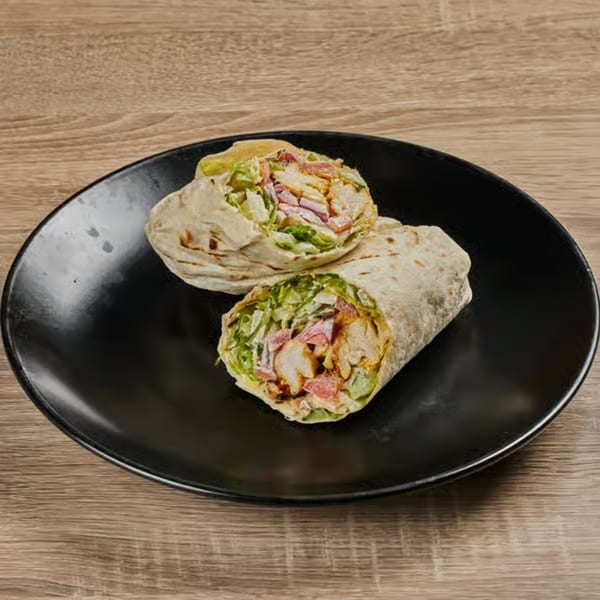 Two Persian chicken wraps, filled with chicken, lettuce, and tomatoes, on a black plate.