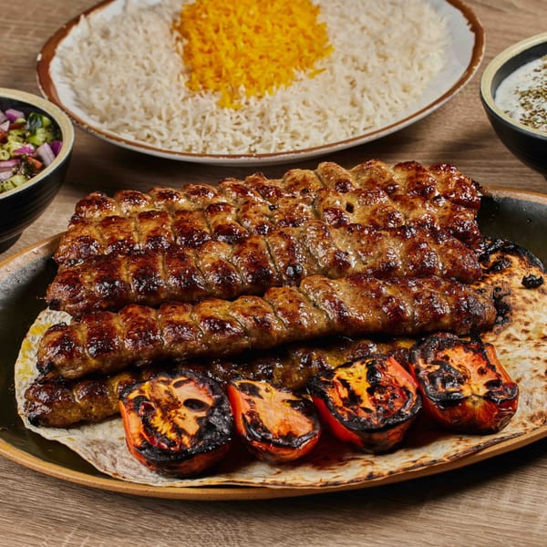 Shahs of Kabob's Persian koobideh kabob with grilled tomatoes, rice, salad, and yogurt dip.
